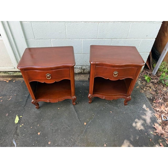 Pair of French Provincial 1 Drawer Nightstands . The pair features shapely front, , 1 drawer with central opening,...