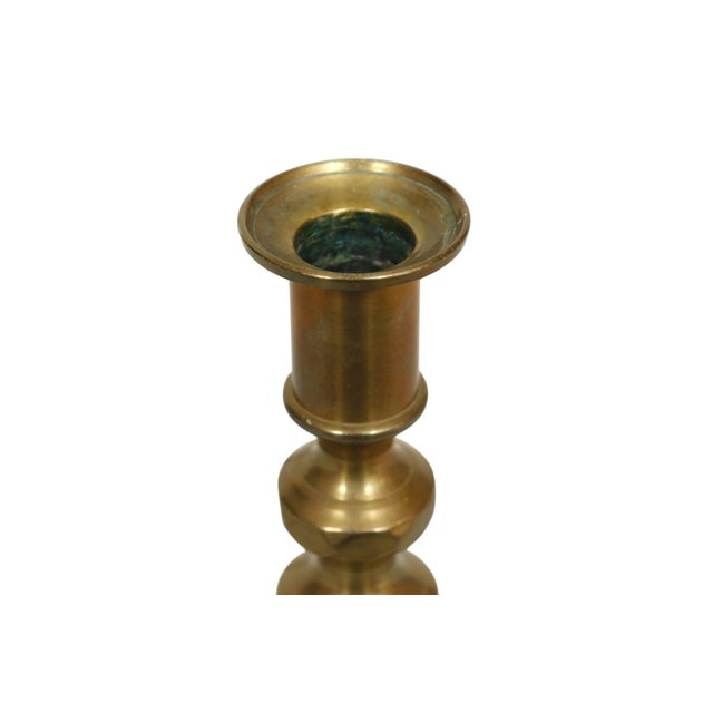 A pair of English candlestick holders made of brass. Turned with beehive shaped columns above square bases. Dimensions per...