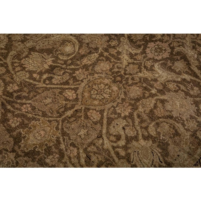A late 19th century Persian Tabriz antique rug, having an abrashed brown field with a dense beige and sand trellis overall...