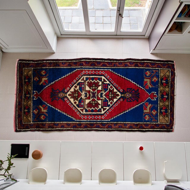This vintage Tashpinar rug features a striking stepped medallion design in deep indigo and vibrant madder red, framed by...