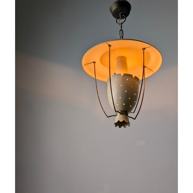 Perforated metal pendant lamp manufactured in Italy during the 1940s. Structural composition features a wide, circular top...