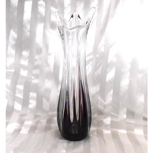 This is a purple and clear art glass vase with a freeform top. The base is purple and the purple comes up the outer edge...