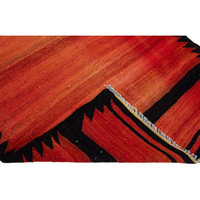 Beautiful vintage Turkish Kilim hand-knotted wool rug with a red field. This piece has black and orange accents in an all-...