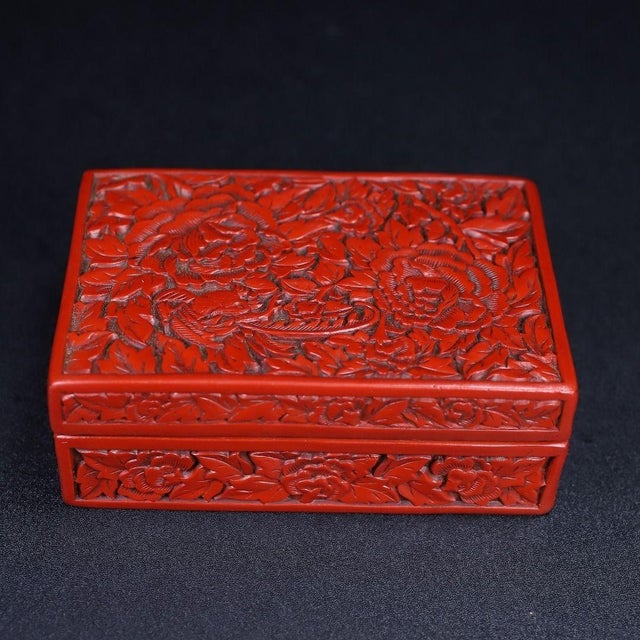 This is an exquisitely crafted carved lacquer box, featuring deep, intricate relief work in a rich, vermilion red. The...