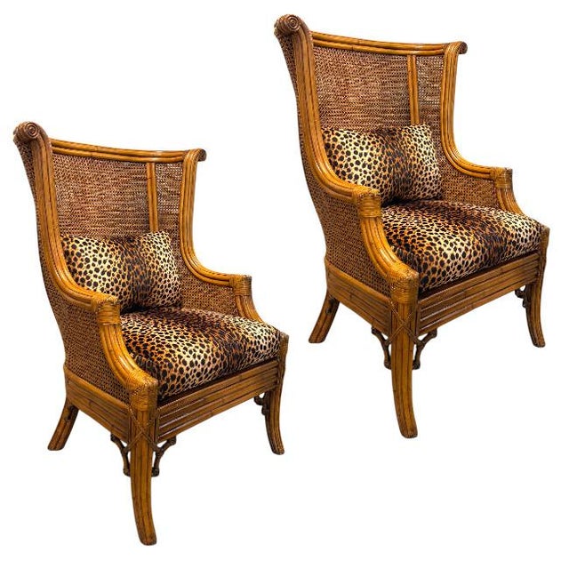 A pair of double-caned rattan wing chairs featuring dramatic high backs, graceful winged silhouettes, and beautifully...