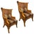 A pair of double-caned rattan wing chairs featuring dramatic high backs, graceful winged silhouettes, and beautifully...