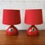 A pair of ceramic table lamps by Bjørn Wiinblad for Rosenthal, finished in a deep red glaze with blue and yellow...