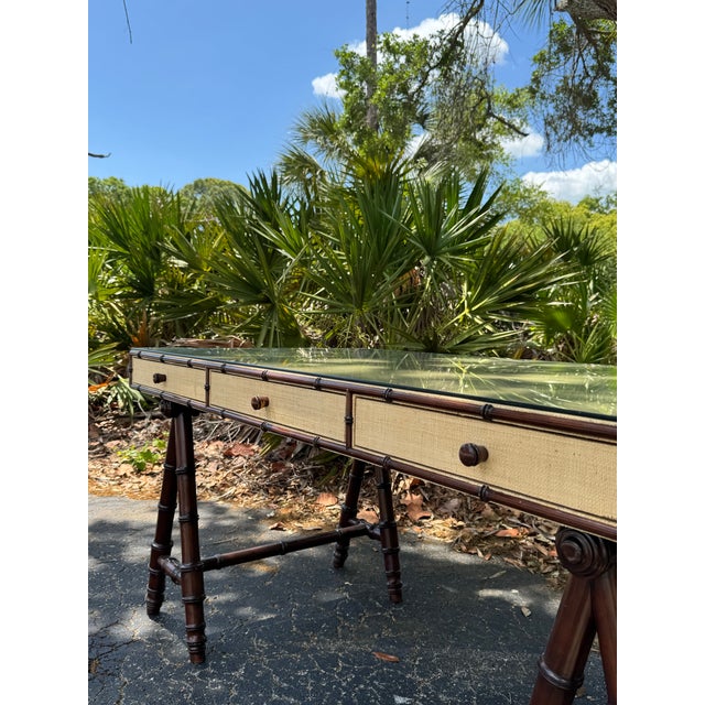 A beautifully crafted Williams Sonoma Home faux bamboo desk, finished in a refined raffia wrap and topped with glass for a...