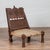 An old Indian rustic wooden low chair from the early 20th century, with hand-woven twine and carved motifs. Charming our...