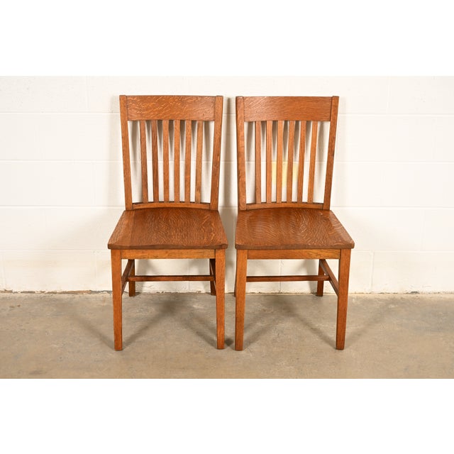 A gorgeous pair of antique Mission or Arts & Crafts period quarter sawn oak spindle back side chairs or dining chairs In...