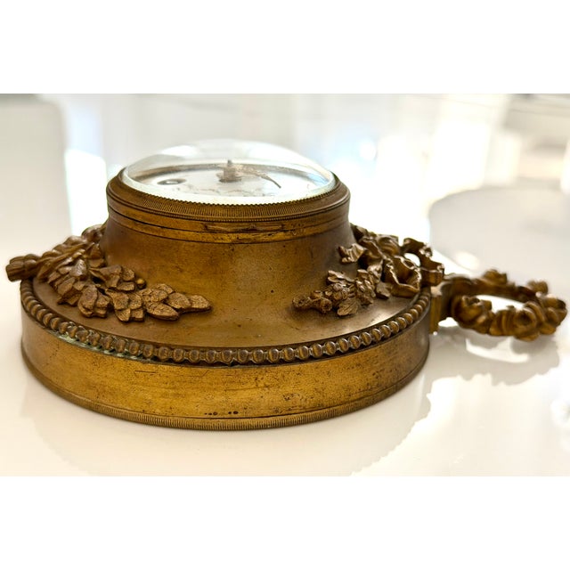 A refined and authentic antique French cartel clock, crafted in heavy gilt bronze, richly decorated with classical floral...