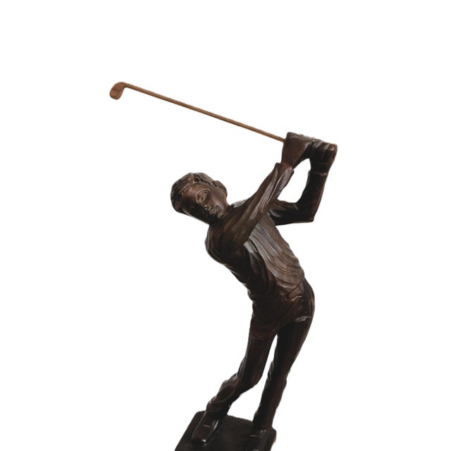 The golf lover carved wooden figural sculpture of a swinging golfer makes a playful decorative accent for a library, den...