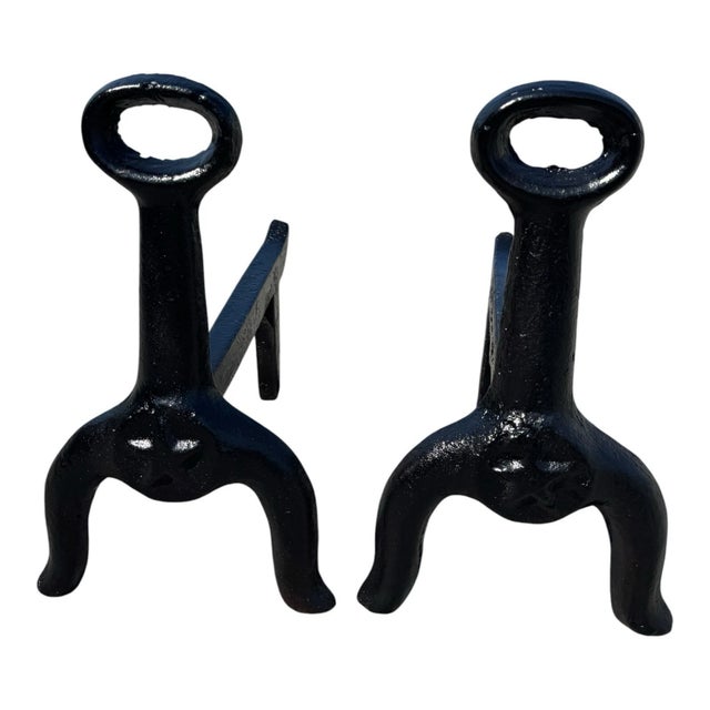 Pair of antique cast-iron fireplace andirons, likely dating to the early 1900s–1920s. Features loop tops, sturdy log...