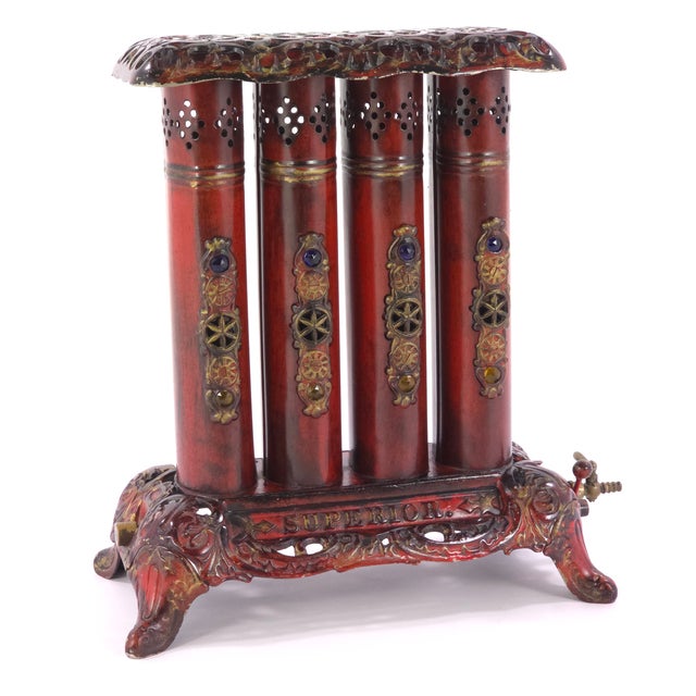 An extraordinary antique Superior four-tube gas parlor heater featuring elaborate Victorian-inspired metalwork, a rich...
