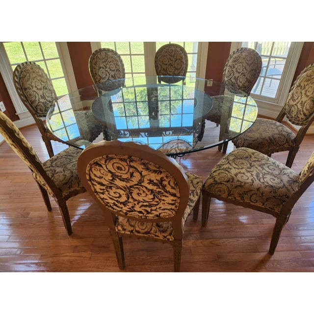 A custom round dining set featuring a thick glass tabletop, substantial base, and eight matching chairs. The six-foot...