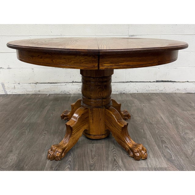 This is a stunning vintage 48” round quarter-sawn oak pedestal dining table with carved lion’s paw or claw feet. It...
