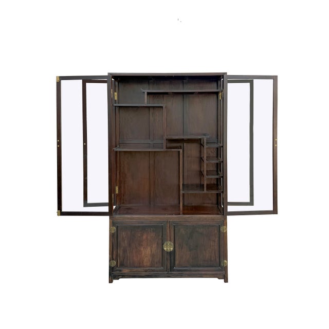 This two-part Chinese display cabinet is crafted from a dark, richly grained wood with a warm, aged patina. The upper...