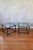 Pair of Mid-Century Modern side tables in the style of Maison Jansen, featuring a dark metal frame with brass accents,...