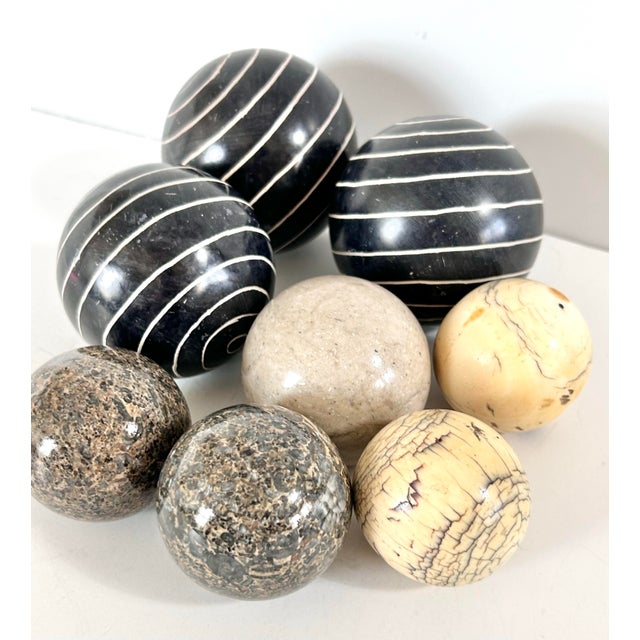 A curated set of 8 decorative stone spheres in mixed materials including marble, granite, and carved soapstone, ideal for...
