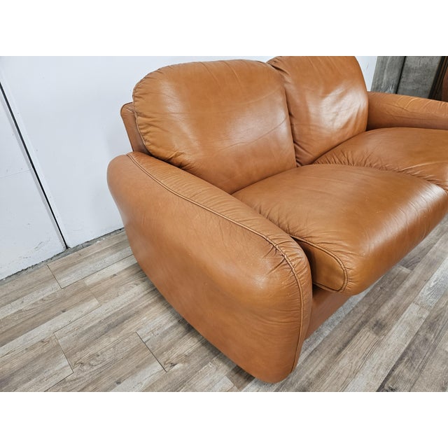 1970s orange leather sofa, Piumotto model, designed by Arrigo Arrigoni for Busnelli. The sofa features a two-seater seat,...