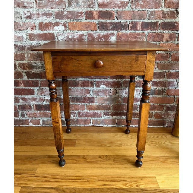 A charming 19th-century American walnut side table featuring finely turned legs, a single dovetailed drawer with original...