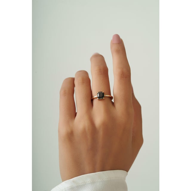 This solitaire ring showcases a 1.66 carat emerald-cut black diamond set in 14k yellow gold. The diamond measuring 6.4 x 7...