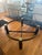 Vintage round glass coffee table with sculptural brass/ bronze-tone and dark wood base. Beautiful statement piece with a...