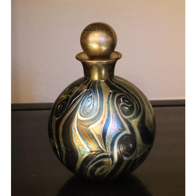 This kaleidoscopic bottle was created to hold a fine perfume. In the typical style of IOW (Isle of White) Glass bottles,...