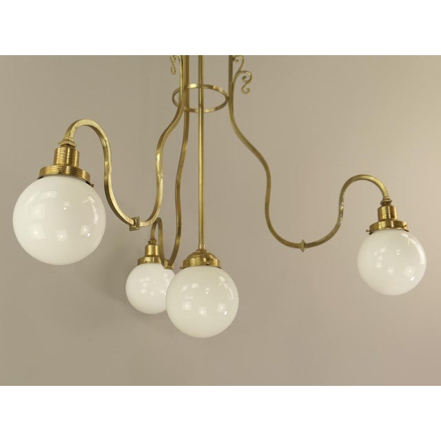 Large Chandelier made of massive brass with 4 opal glass shades. Well suited for high rooms. There are 2 pieces that are...