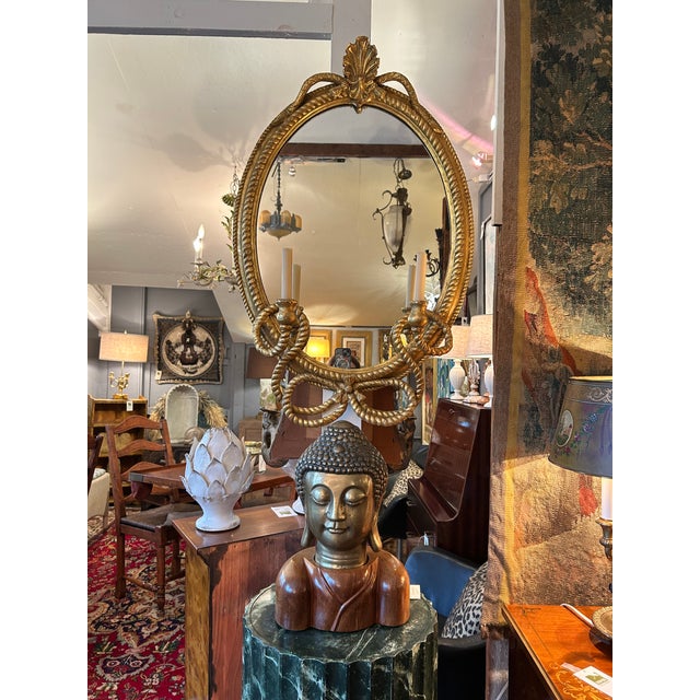 Lovely oval antique giltwood mirror having twisty rope style appearance, bow at the bottom and carved embellishments, with...