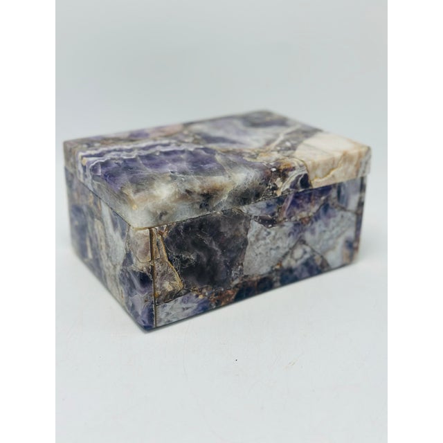 This is a small lidded decorative stone trinket box carved from a natural semi-precious stone, most likely sodalite....