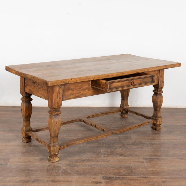This handsome pine library table with one drawer has heavily turned legs, and unique carved/curved stretchers. The top and...