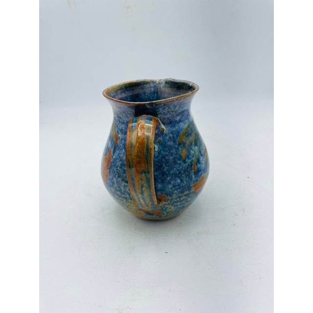 Great color and style to this lovely small pottery pitcher. The pitcher measures 4 inches wide 5 inches tall and 5 inches...