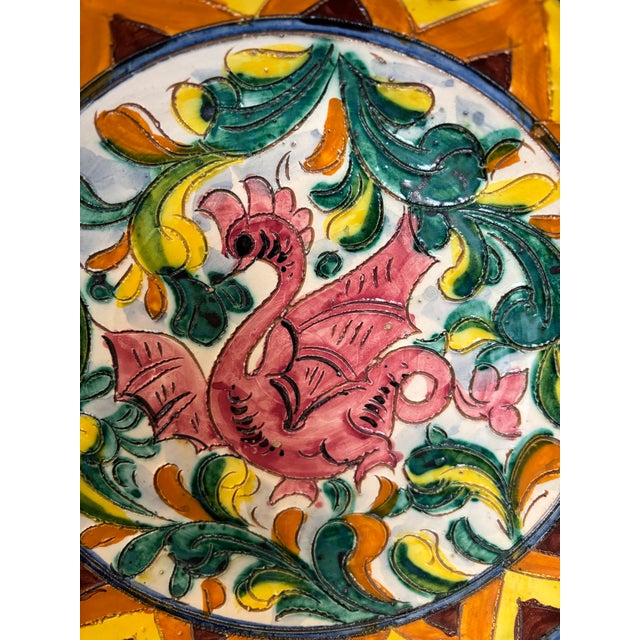 Striking vintage hand-painted majolica-style decorative pottery plate featuring a stylized pink mythical bird or griffin...