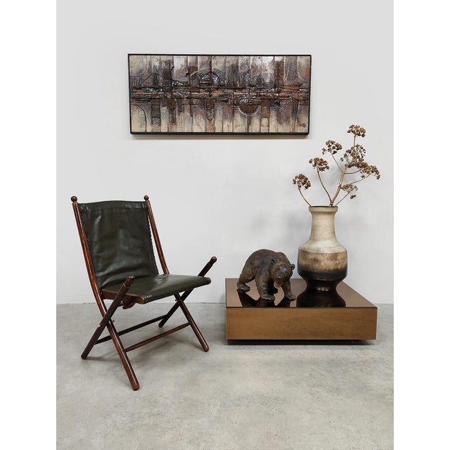 Sit in Style! with this vintage leather folding chair from the 1950s, featuring a classic campaign chair design. The dark...