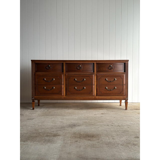 This vintage walnut 9-drawer dresser by Ward Furniture features a clean, symmetrical facade with framed drawer fronts,...