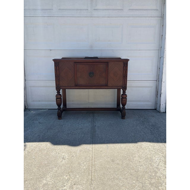 We have a beautiful vintage Jacobean Revival cabinet for sale featuring rich walnut tones, turned legs, carved details,...