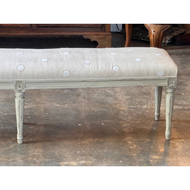 A Louis XVI painted bench, over five feet long, on six turned and fluted tapering legs with carved rosette blocks. Worn...