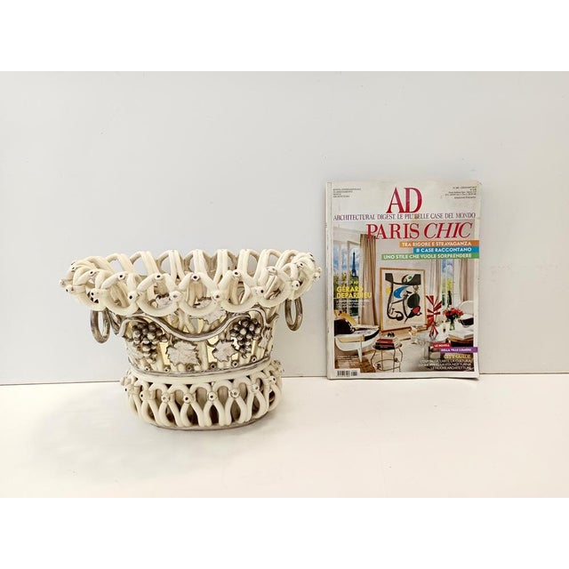 Made in France, 1850 ca. This creamy white fruit bowl with coiled frame and handles with movable silvered rings is made in...