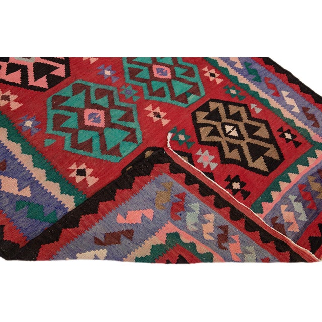 Beautiful vintage Turkish Kilim hand-knotted wool runner with a red field. This rug has a purple frame and multicolor...