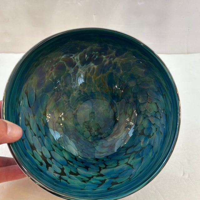 Hand blown art glass bowl in swirls of greens and blues with mixed colors on the exterior. Very attractive and takes on...