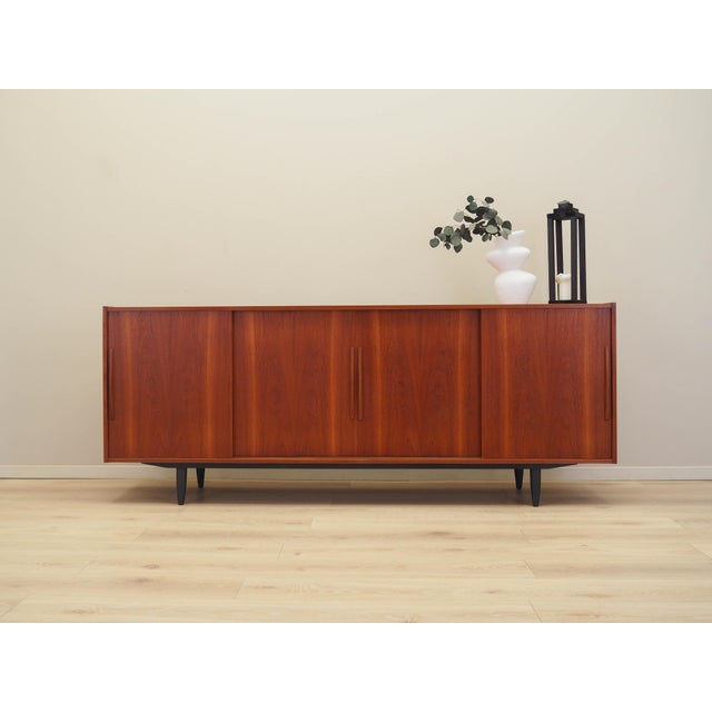 The sideboard was made in the 1970s in Denmark. The structure is covered with teak veneer. The legs are made of solid wood...