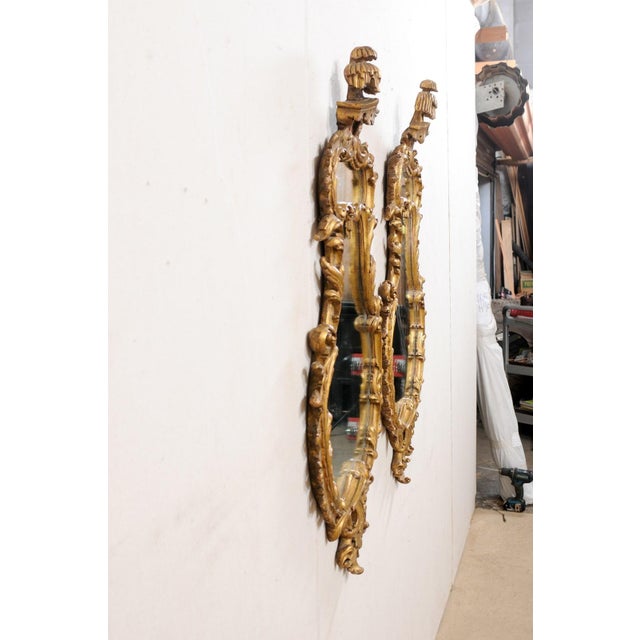 An Italian pair of carved and gilt decorative wall mirrors from the mid 20th century. These vintage mirrors from Italy...