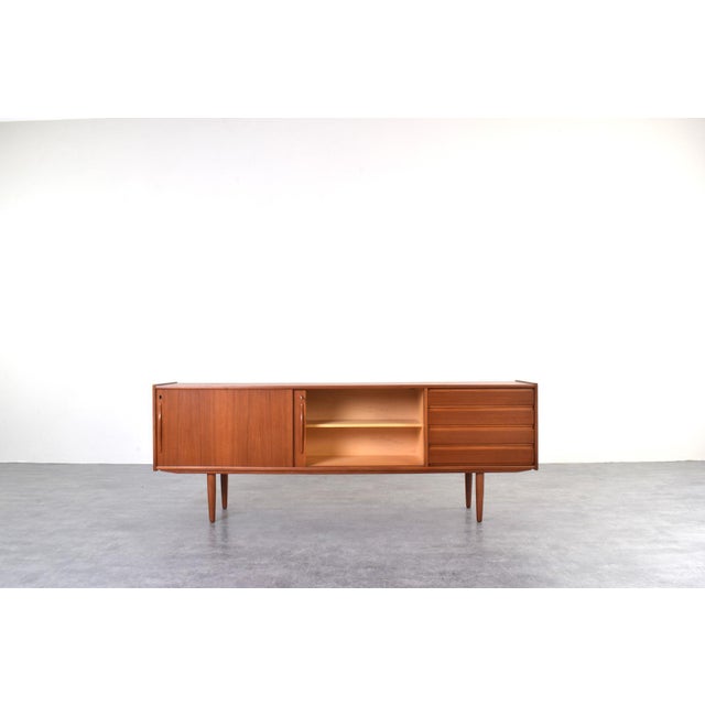 This teak sideboard was manufactured in Denmark in the 1960s. The piece of furniture has four drawers and a sliding,...