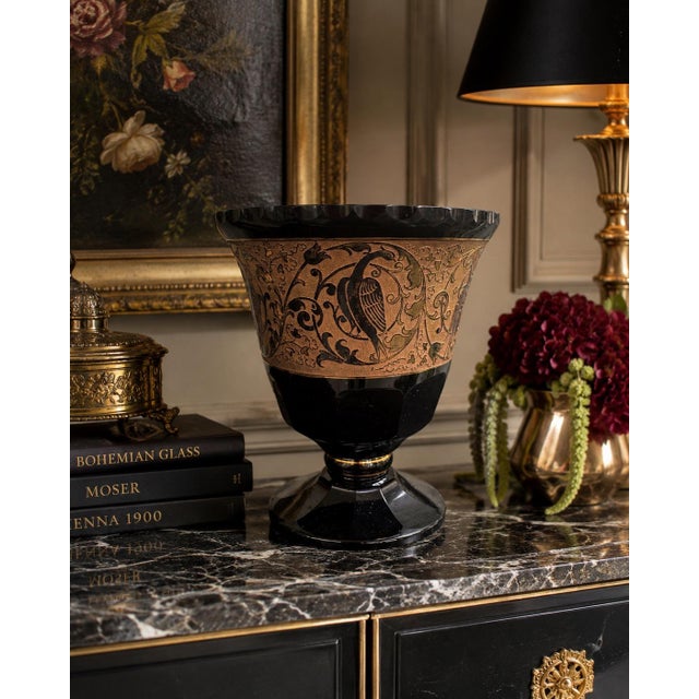An elegant antique Bohemian amethyst glass footed bowl dating to the early 20th century, featuring a richly detailed gilt...