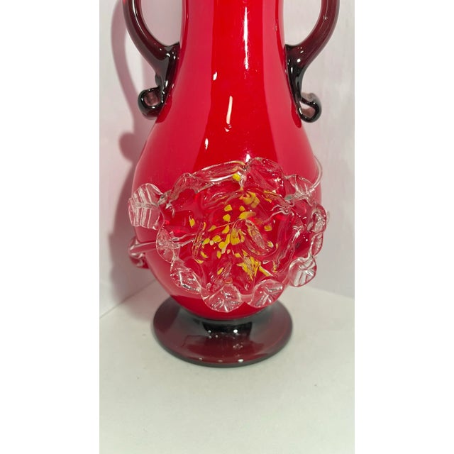 Bright red vase with beautiful dark purple handles and base. It has a floral shape in clear glass with yellow accents and...