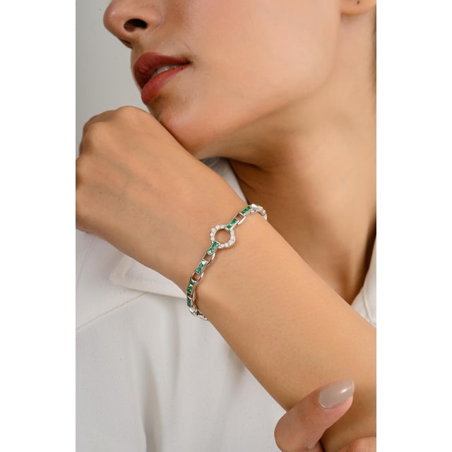 This 14k white gold tennis bracelet features vibrant emeralds in a sleek channel setting, beautifully complemented by...