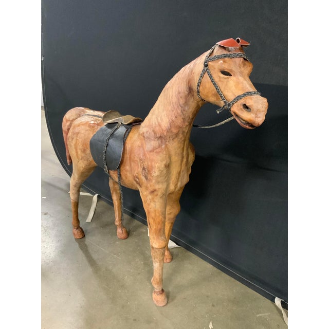 A three feet tall vintage decorative sculptural leather covered horse figure posed standing with its head turned and neck...