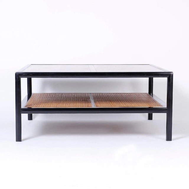 Chic Baker, two-tiered coffee or cocktail table with a sleek black lacquer frame, walnut top, and a caned lower plateau...