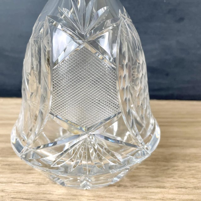 Antique liquor decanter with cut grapes and vines and a cut crosshatching. Paneled hexagonal stopper has a controlled...